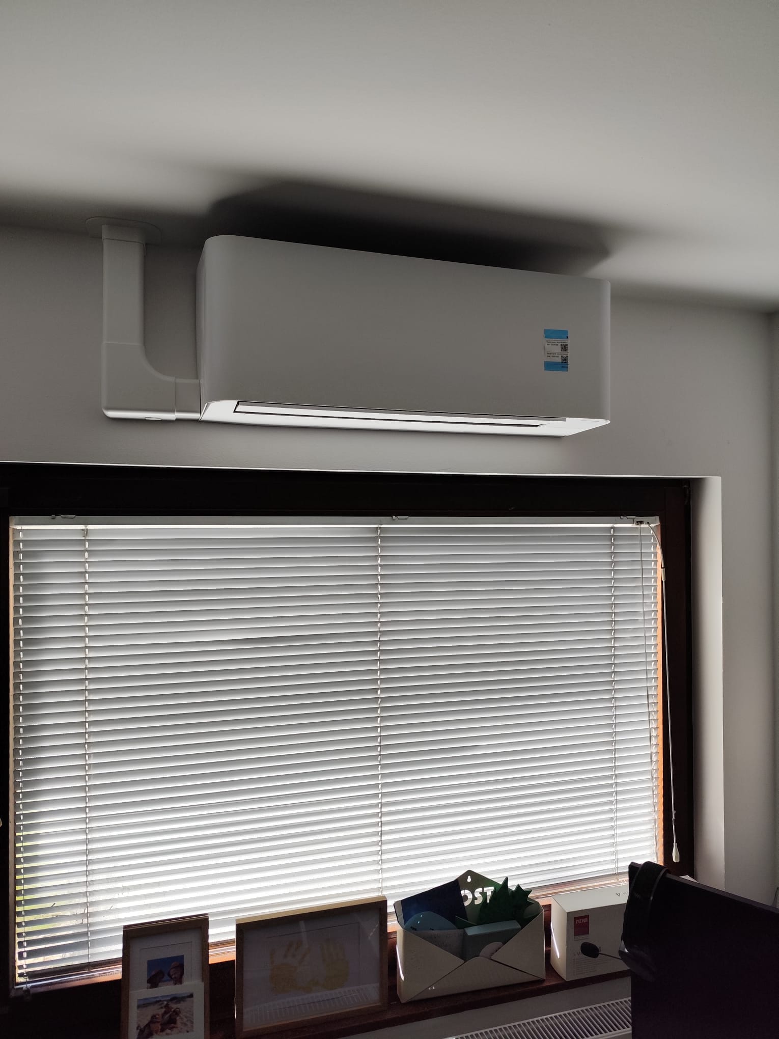Moderne Split-Klimaanlage im Berliner Büro über Fenster mit Jalousien montiert