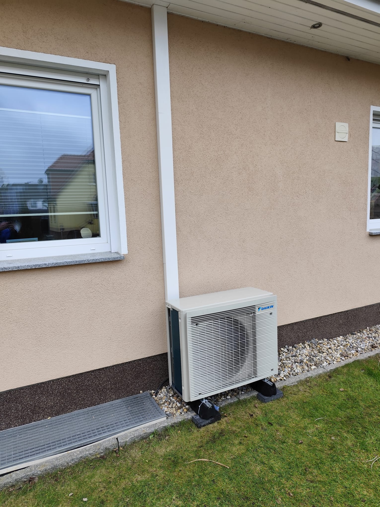 Daikin Wärmepumpen-Außengerät an der Hausfassade neben dem Garten installiert